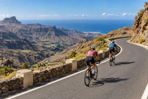 Zwei Radfahrer mit Helm auf einer Bergstraße über einer Schlucht und dem Atlantik